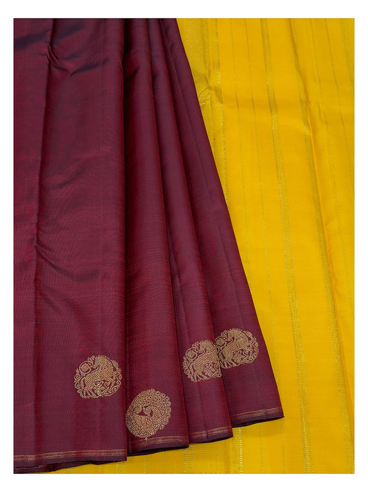 Deep wine handwoven Kanchipuram silk saree paired with bright contrast yellow section and gold-toned motifs