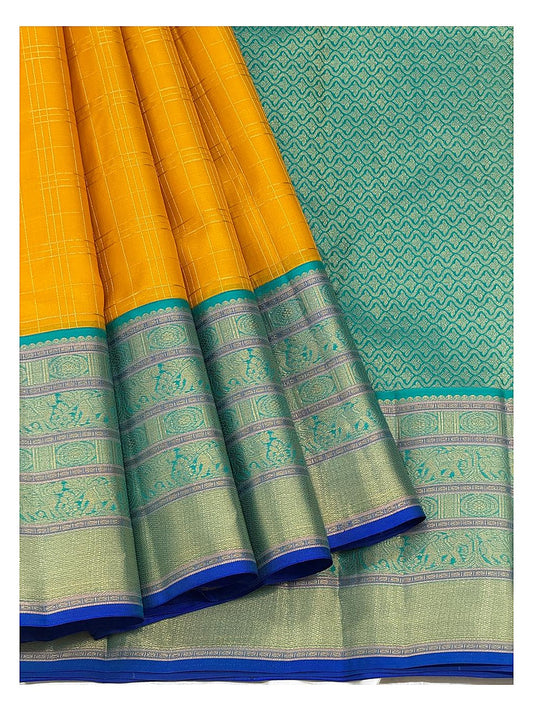 Draped mustard saree with teal patterned pallu and broad woven border panels