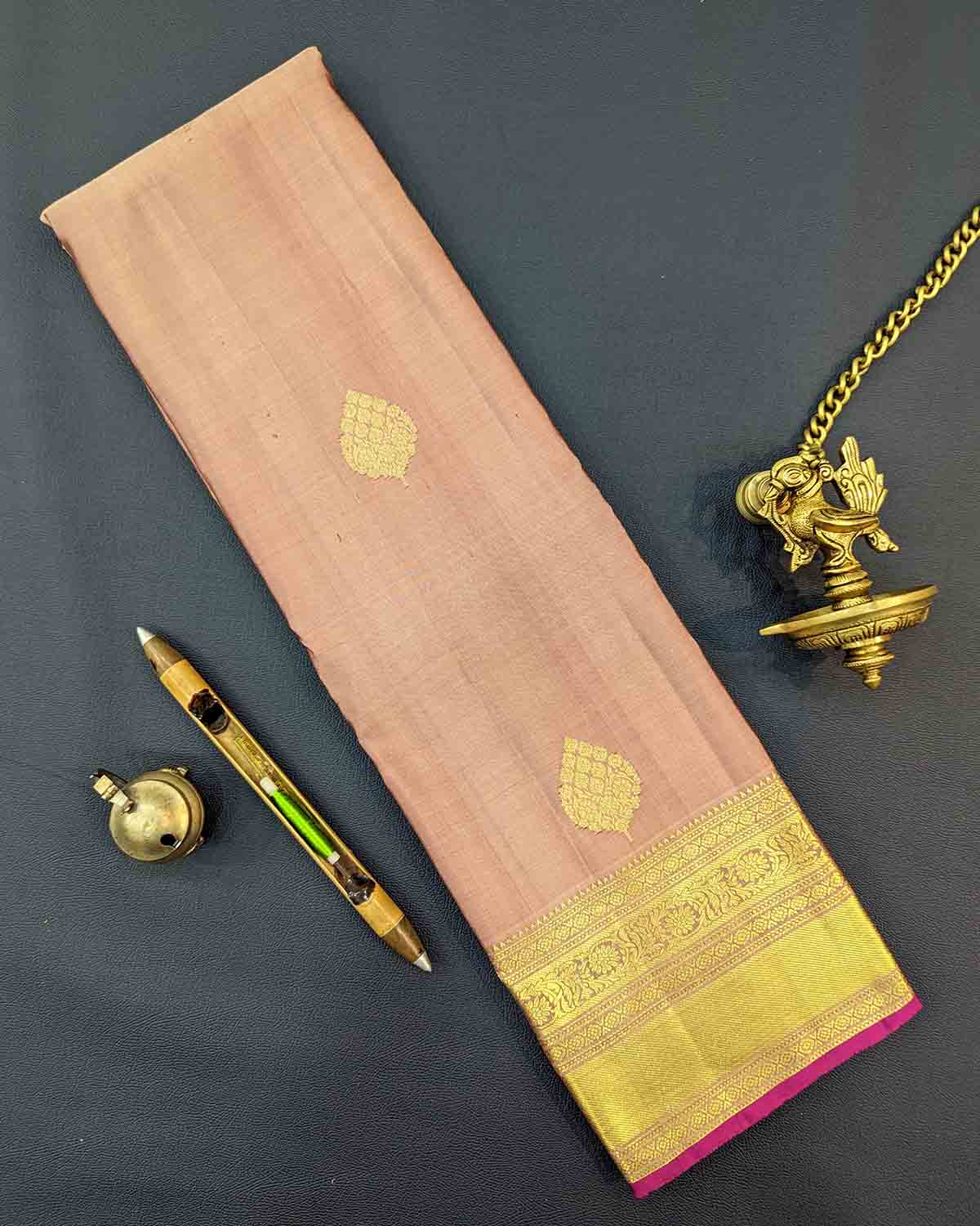 Traditional gold silk saree with leaf buttas, gold border, and intricate pink designs.