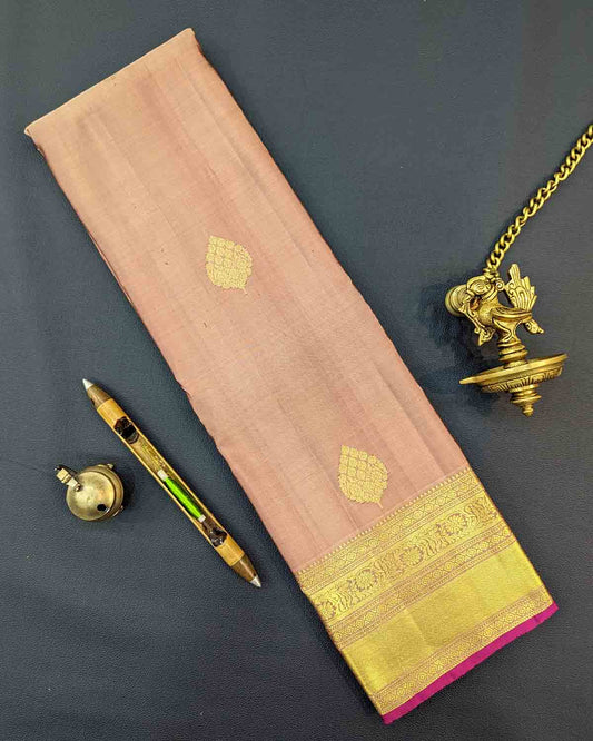 Traditional gold silk saree with leaf buttas, gold border, and intricate pink designs.