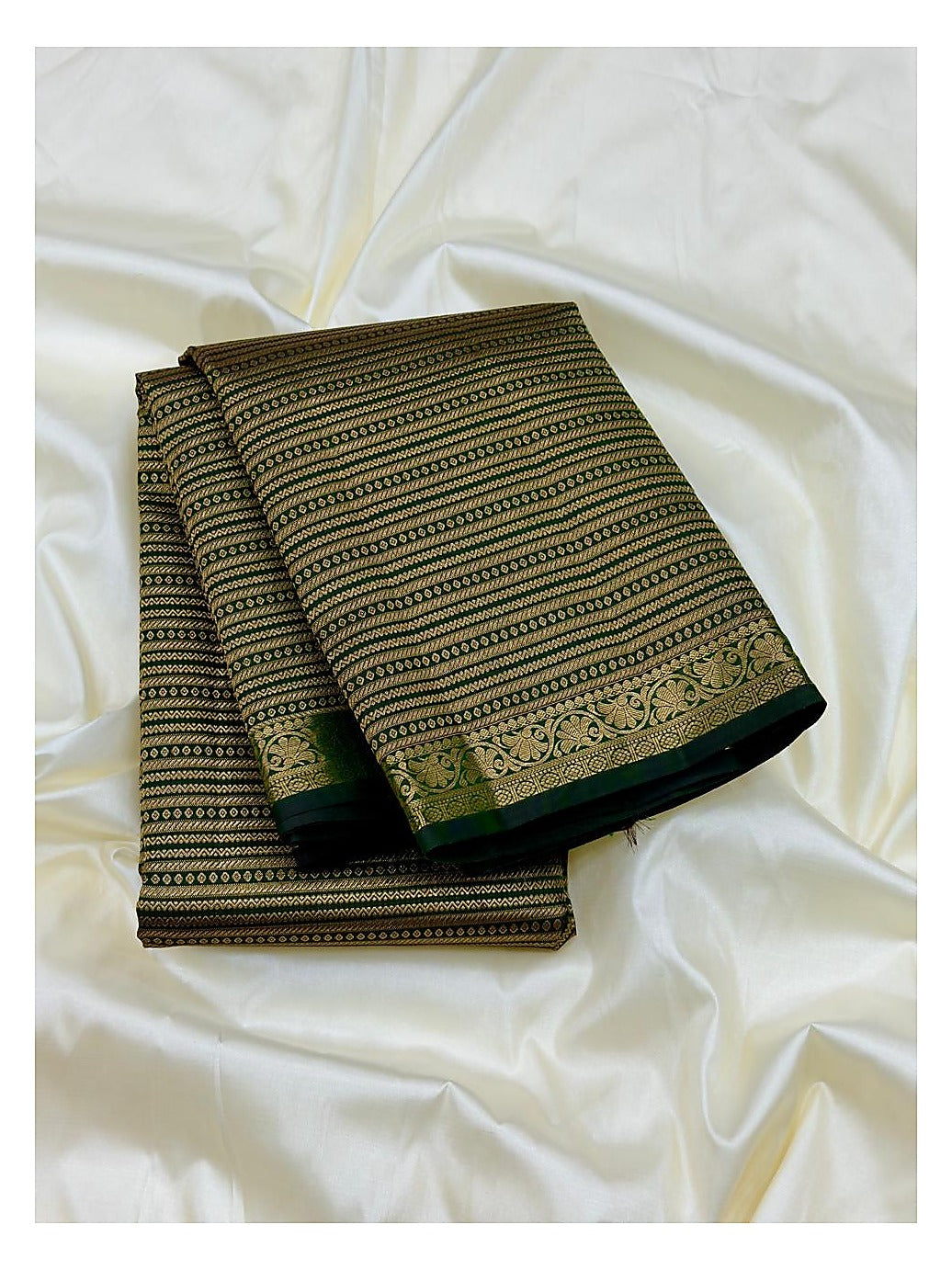 Folded deep green Kanchipuram silk saree with gold-toned woven stripes and floral border