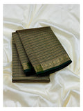 Folded deep green Kanchipuram silk saree with gold-toned woven stripes and floral border