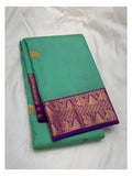 Folded aqua green handwoven Kanchipuram silk saree with purple contrast border and gold-toned woven motifs