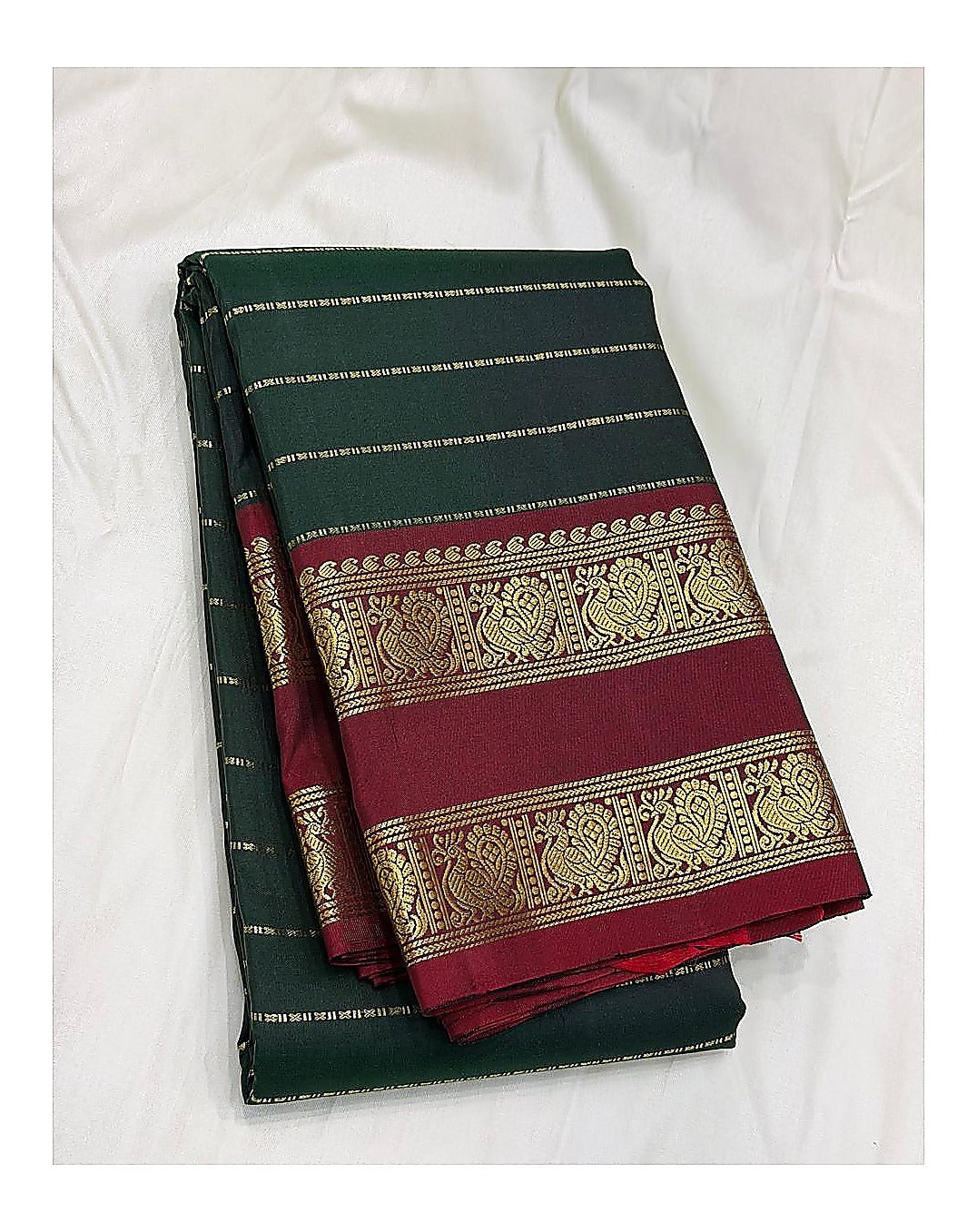 Handwoven Kanchipuram silk saree in deep green with maroon peacock border, folded view