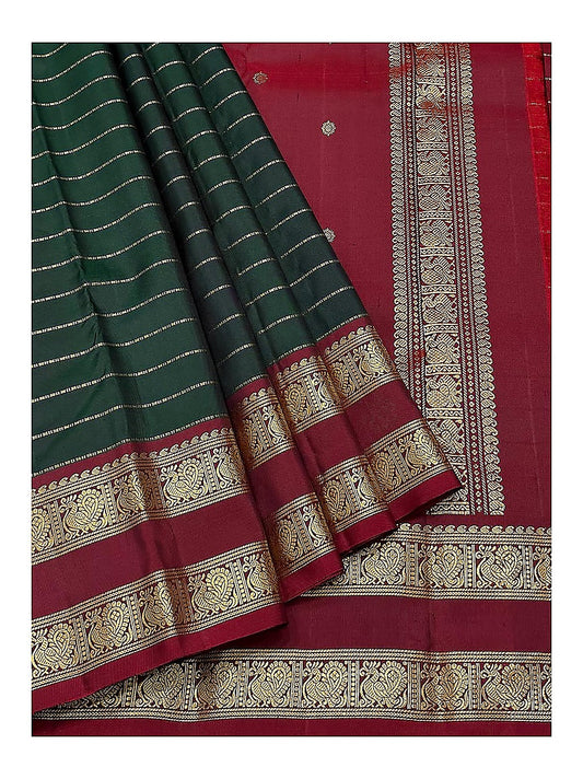 Close view of deep green body, maroon pallu and gold-toned peacock border on handwoven Kanchipuram silk saree