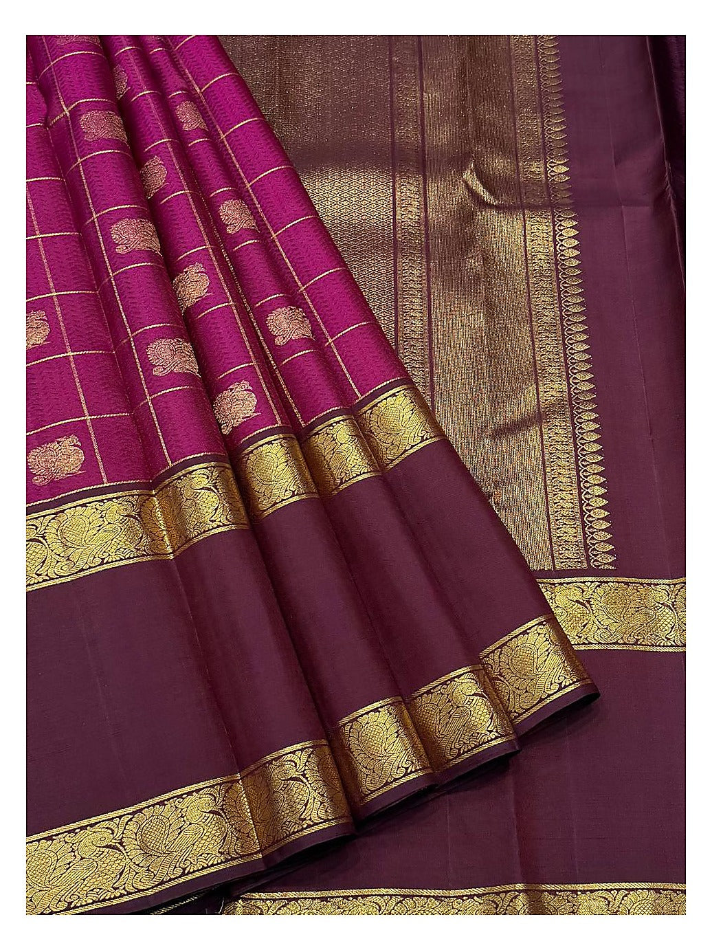 Draped view showing the deep magenta checks, plum zari pallu, and peacock-style border