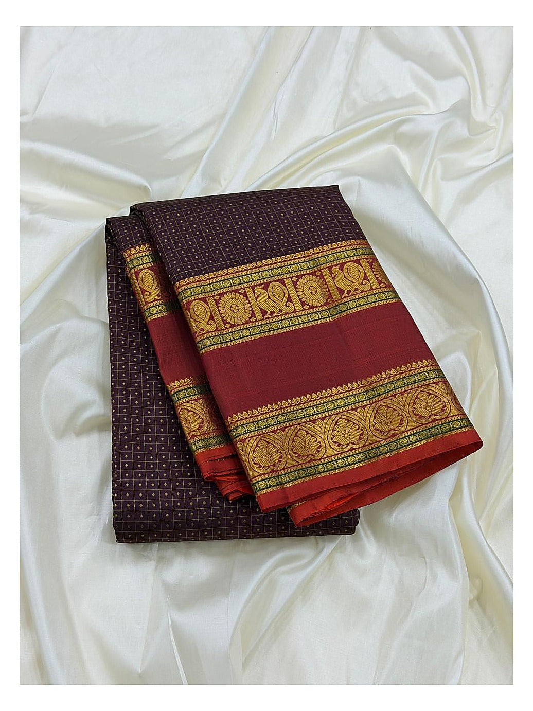Handwoven Kanchipuram silk saree folded to show the deep plum body with fine butta pattern and maroon border with gold-toned woven motifs