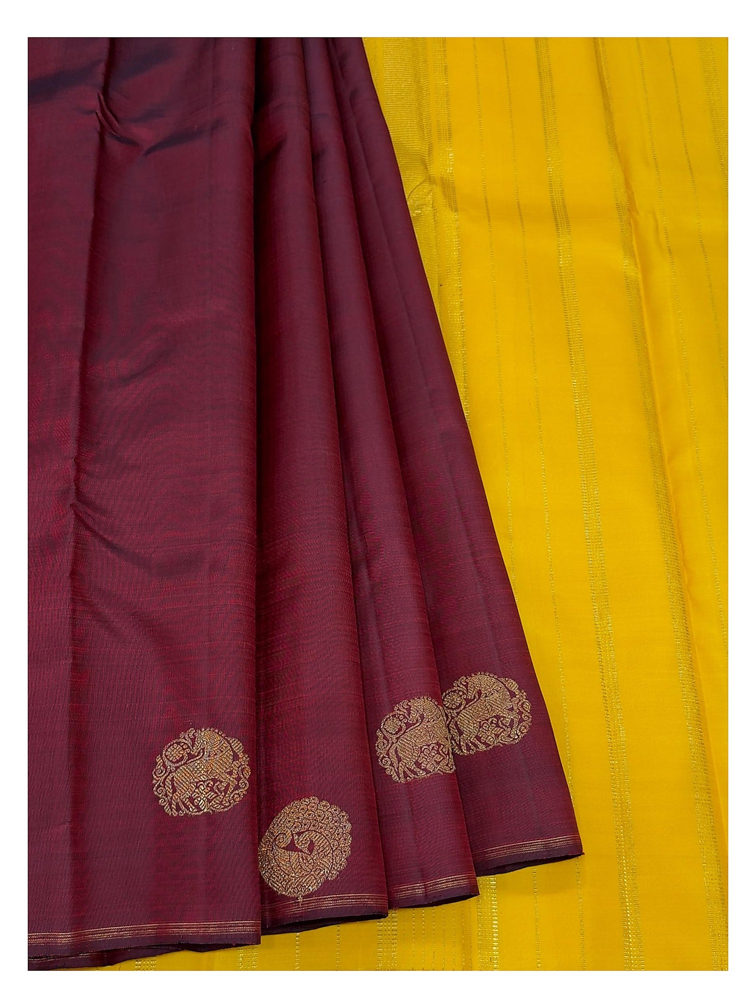 Deep wine handwoven Kanchipuram silk saree paired with bright contrast yellow section and gold-toned motifs
