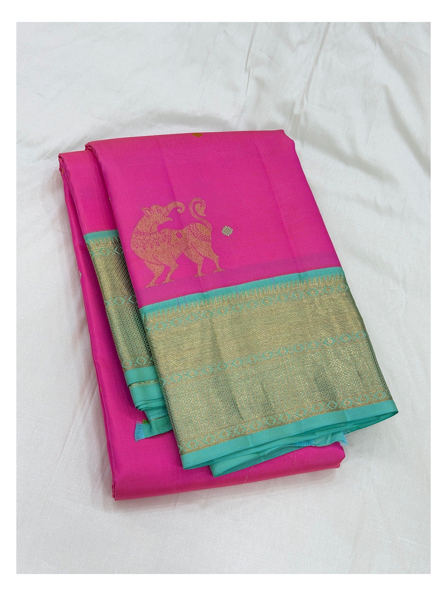 Handwoven Kanchipuram silk saree in bright pink with aqua blue zari border and elephant motif.