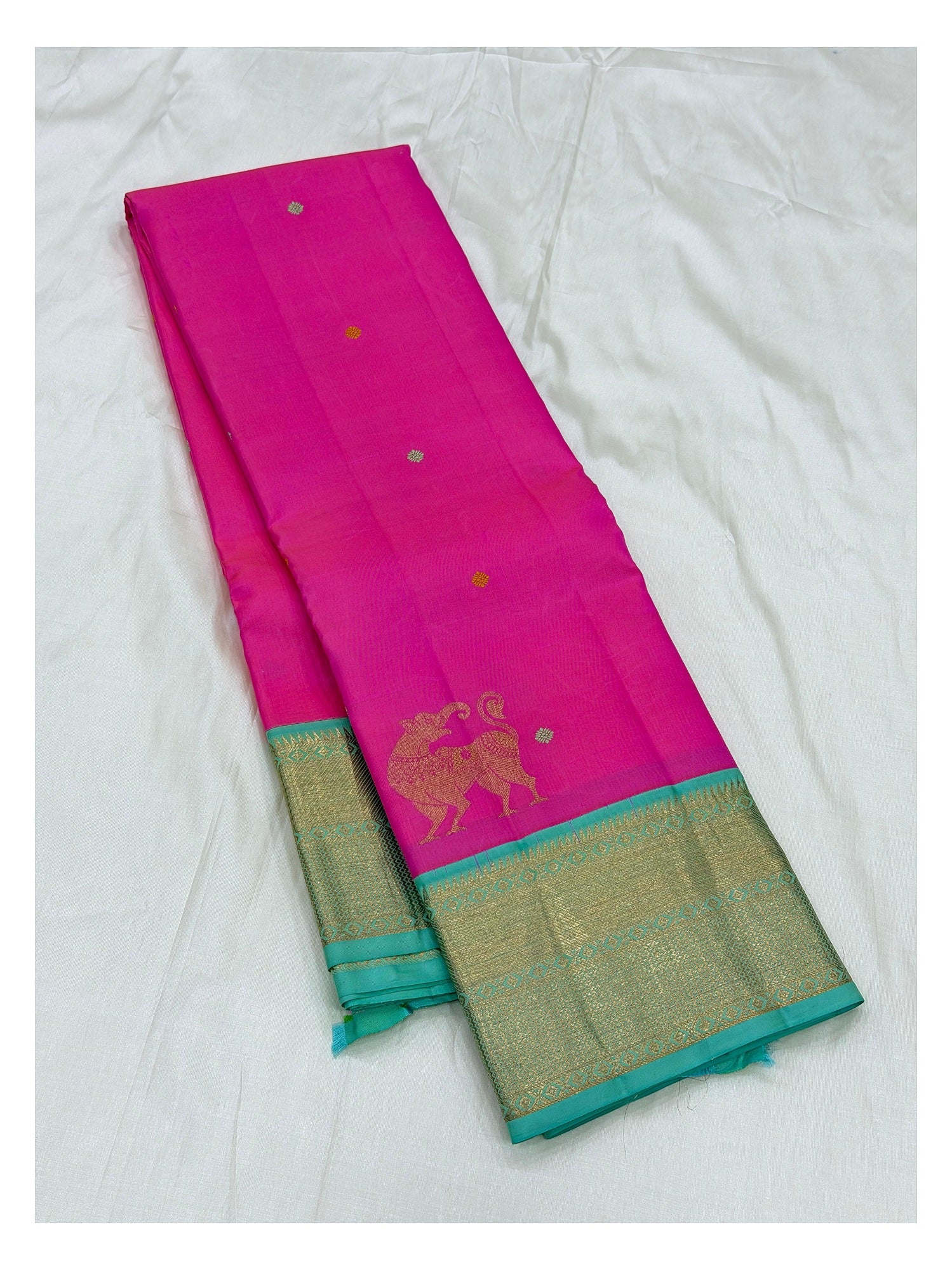 Folded view of the pink handwoven Kanchipuram silk saree with aqua zari border and buttas.