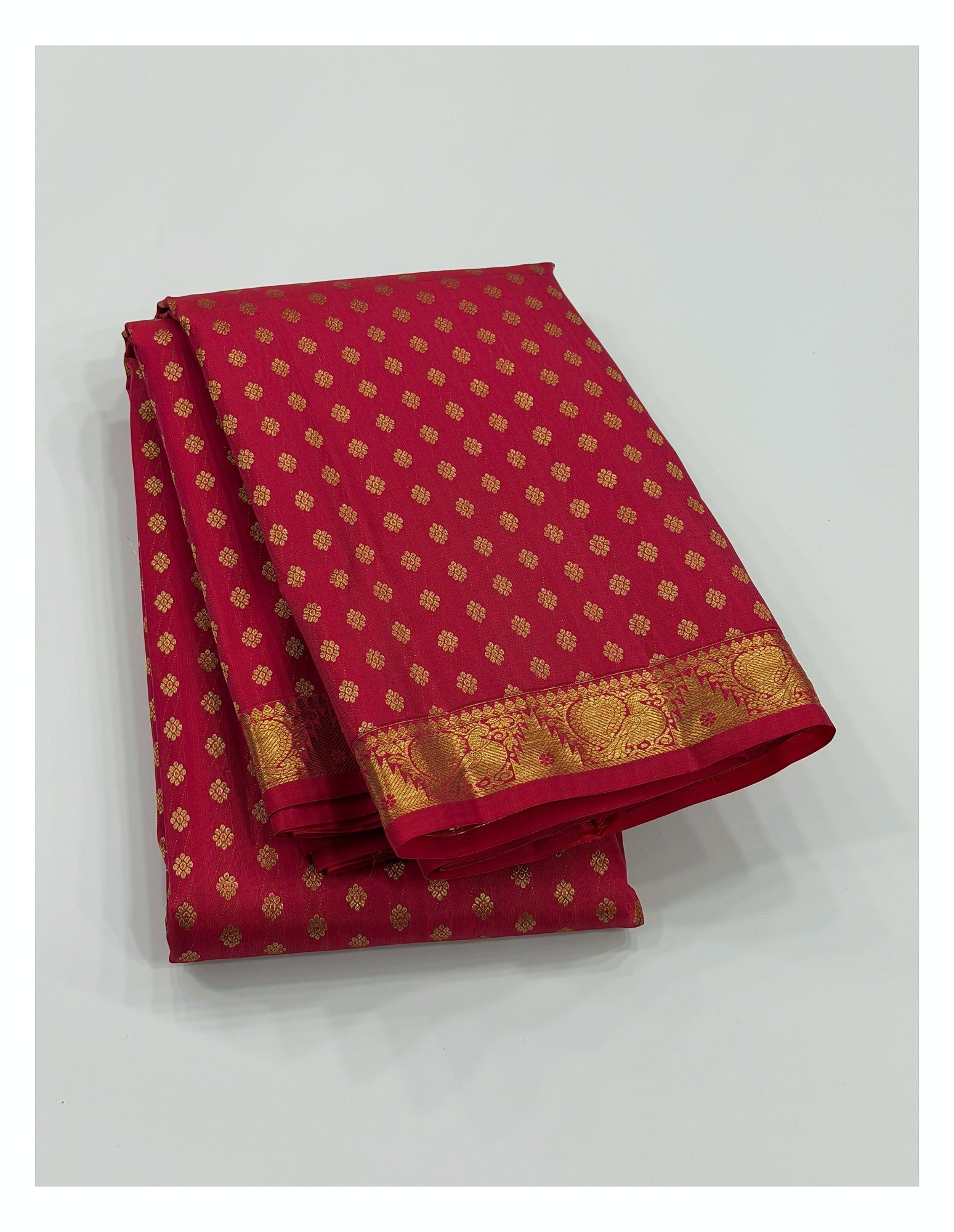 Rani pink handwoven Kanchipuram silk saree folded to show gold buttas and zari border