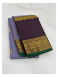 Folded handwoven Kanchipuram silk saree in lavender and deep plum with wide gold-toned woven border and green selvedge