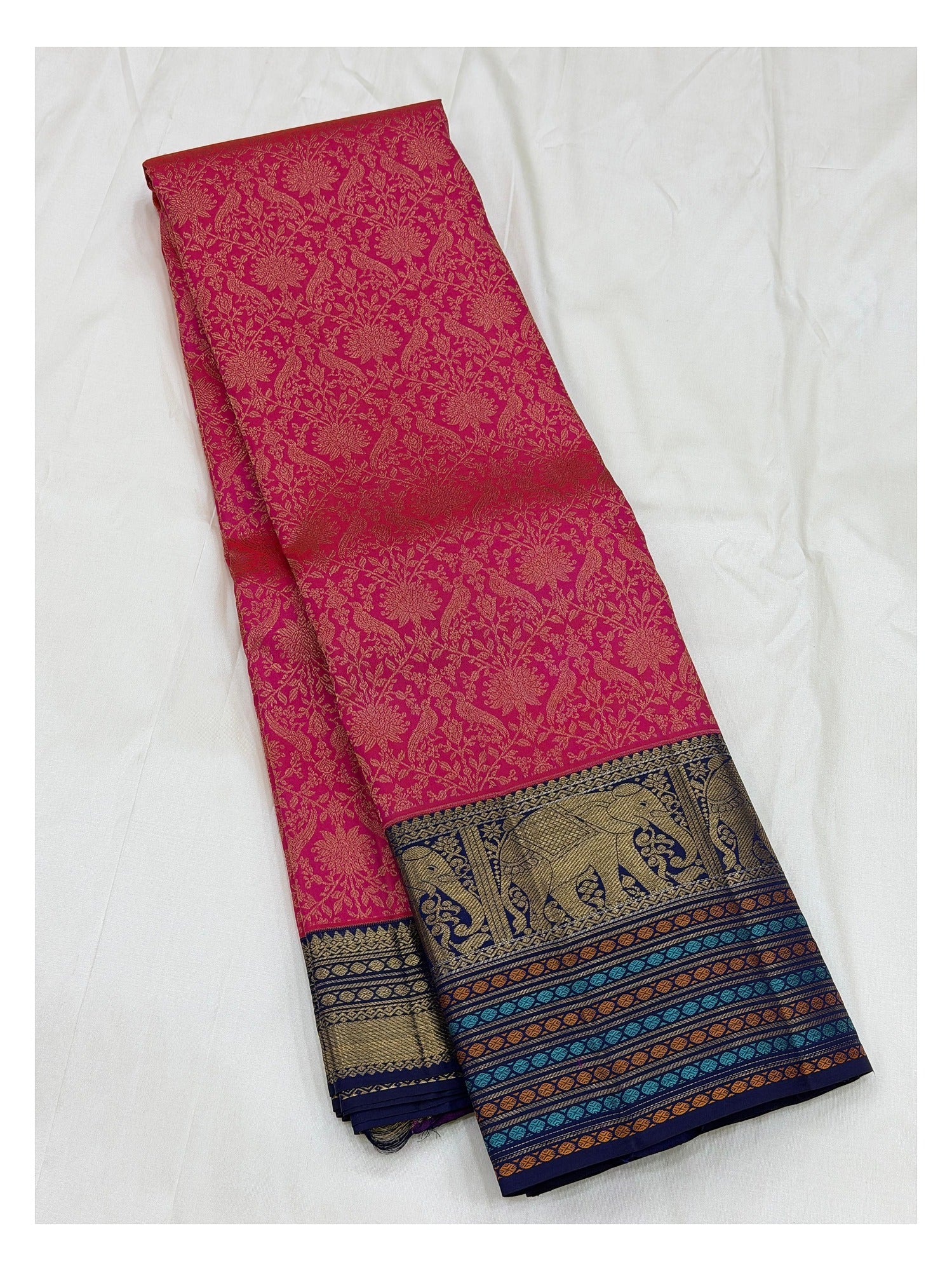 Full folded view of the pink Kanchipuram silk saree with zari motifs and contrast navy elephant border