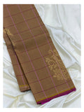 Folded cocoa brown Kanchipuram silk saree with magenta checks and gold-toned floral motif detail