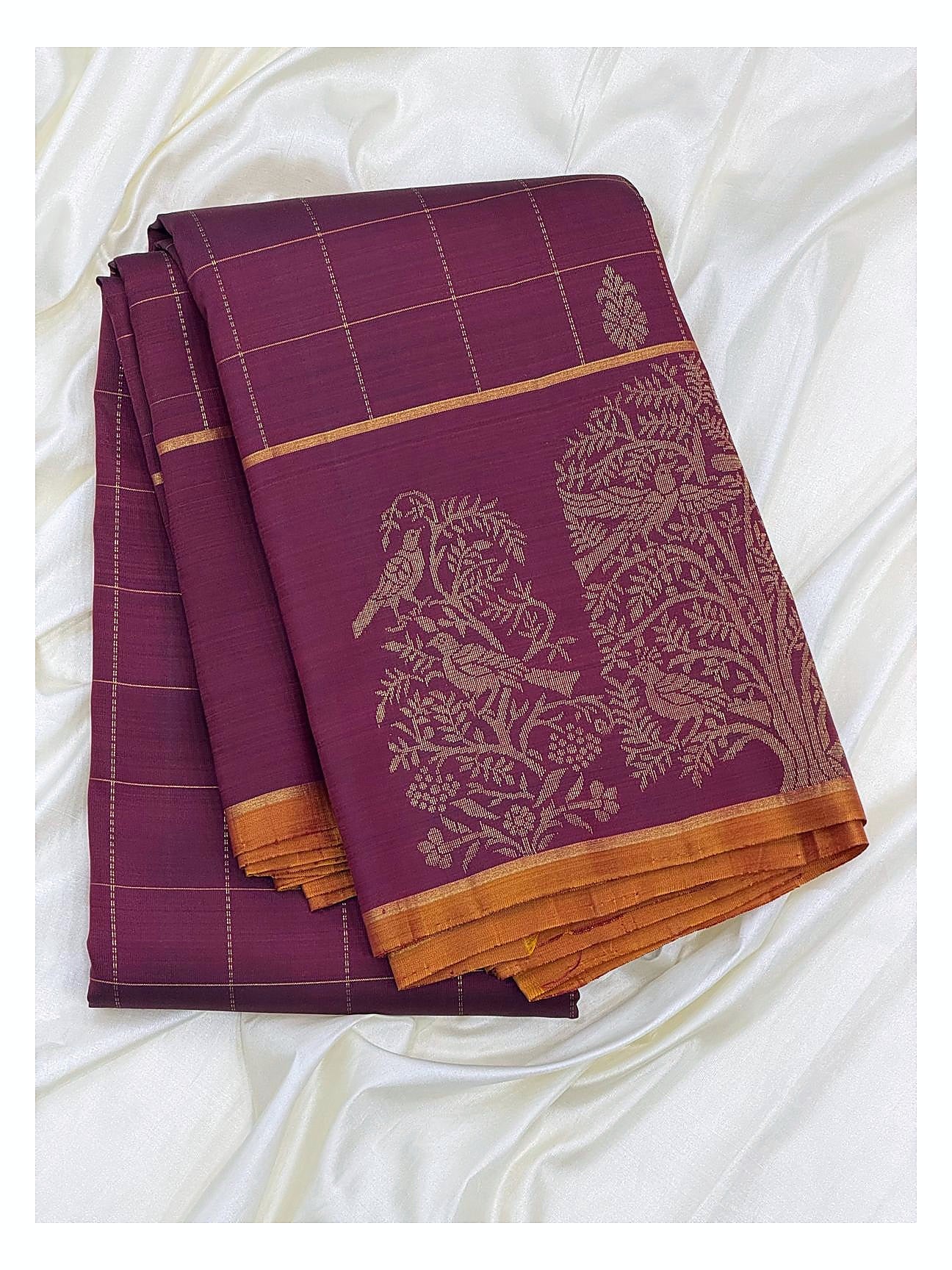 Folded magenta handwoven Kanchipuram silk saree with gold butta motifs and bird motif border