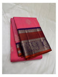Folded bright pink pure silk saree with purple and rust-toned peacock border
