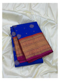 Royal blue pure silk saree folded with broad gold-toned woven border and magenta contrast