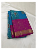 Folded sky blue Kanchipuram silk saree with teal ikat-style pallu and magenta zari border